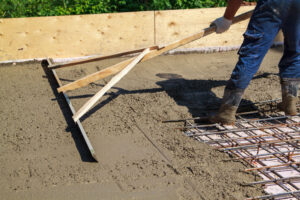 worker leveling fresh concrete slab with a special working tool